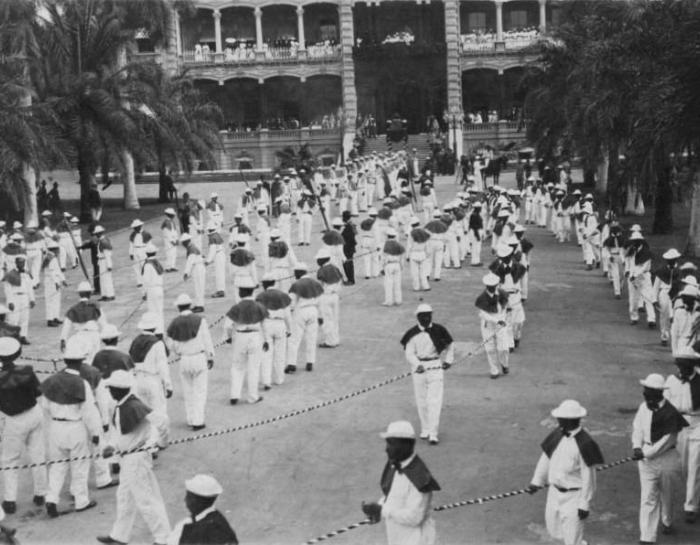 Funeral procession of Queen Liliʻuokalani with Native Hawaiian stevedores in white carrying her casket at ʻIolani Palace.